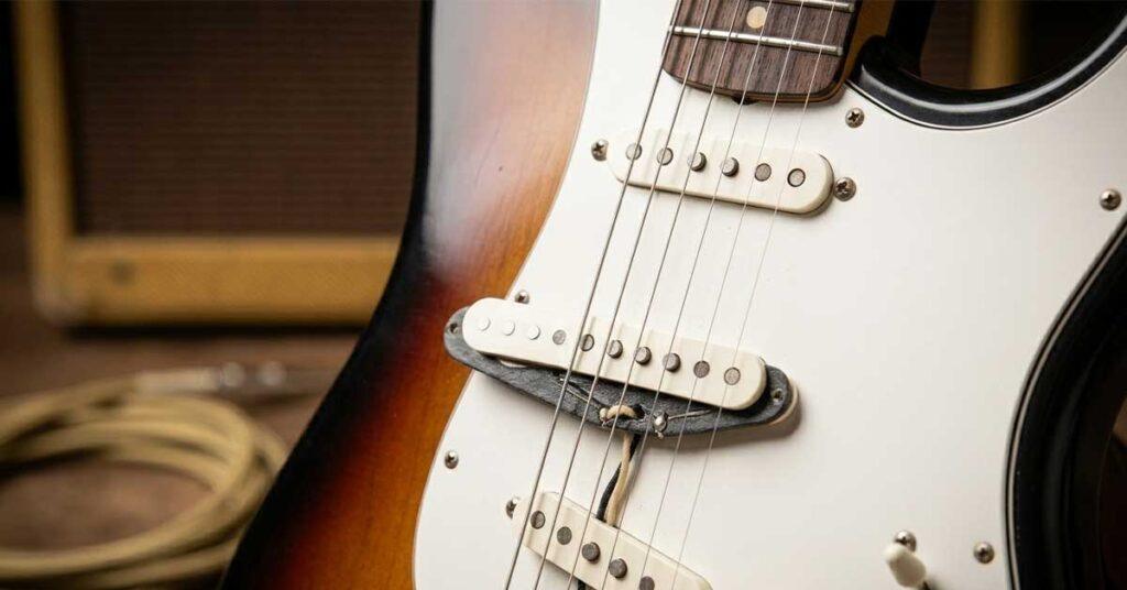 Close-up dos três captadores single-coil brancos em uma guitarra Fender Stratocaster sunburst.